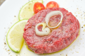 Steak tartare closeup  with lemon slices on white plate