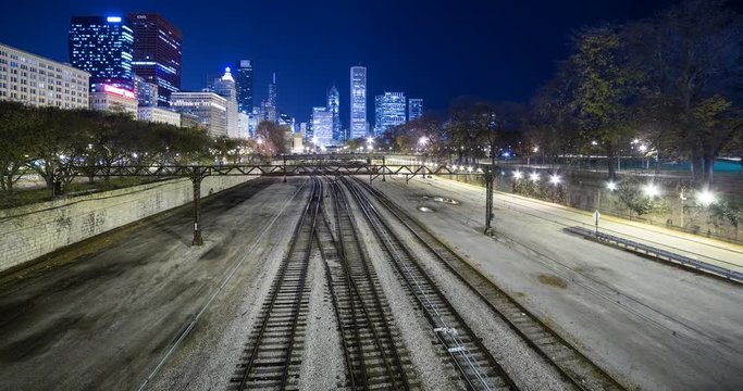 Chicago, Illinois, USA - rails and the Chicago L / Elevated near Millennium Park with illuminated Skyline in the background at night - Timelapse with zoom out 