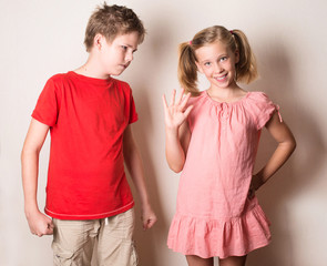 Children in different moods. Sister teasing her brother, fake smile