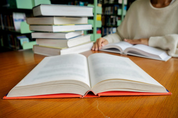 Reading concept. Vintage tone of asian woman reading book in library. Retro filter effect,soft focus,low light.(selective focus).