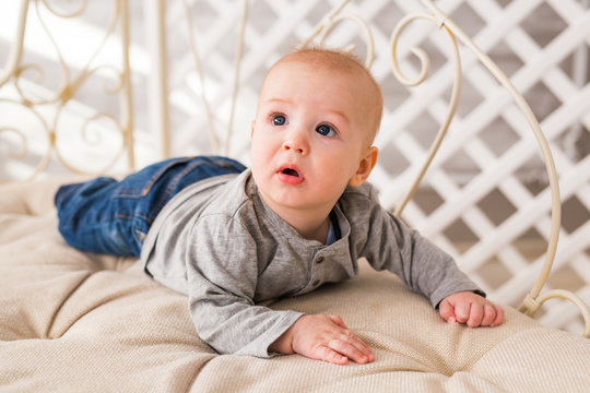 Adorable baby boy in white sunny bedroom. Newborn child relaxing. Family morning at home.