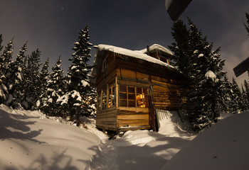 House Chalet during a snowfall in the trees winter forest at nig