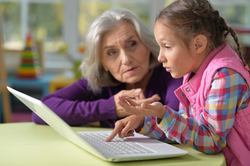 Fototapeta na wymiar Grandmother and granddaughter with laptop