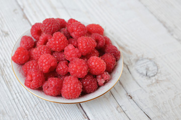 Raspberries in a bowl on a wooden table