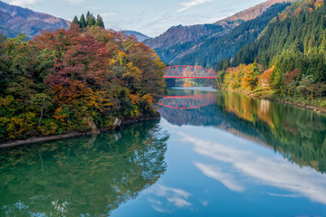 Fototapeta na wymiar Tadami river and red bridge in autumn season, Fukushima, Japan