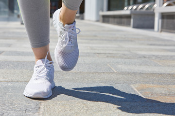 Woman running with white shoes outdoor in the city in a sunny da