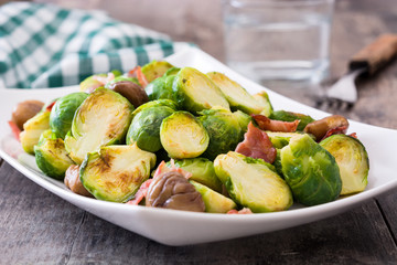 Brussels sprouts with chestnuts and bacon on wooden table

