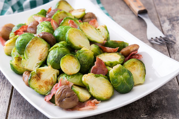 Brussels sprouts with chestnuts and bacon on wooden table
