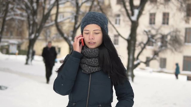 Outdoors winter shot of a young brunette girl talking by phone