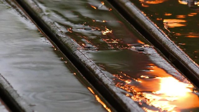 Deque de madeira na chuva com reflexo de luz.