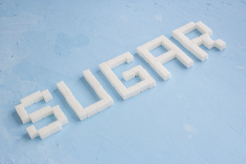 word is written from sugar cubes on blue background, sugar