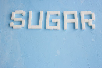 word is written from sugar cubes on blue background, sugar