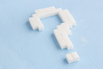 Question mark made of sugar cubes on blue background, symbol ?