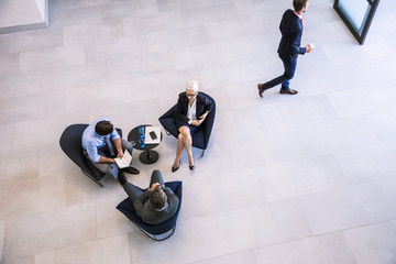 High angle view of businesswoman and men meeting in office atrium