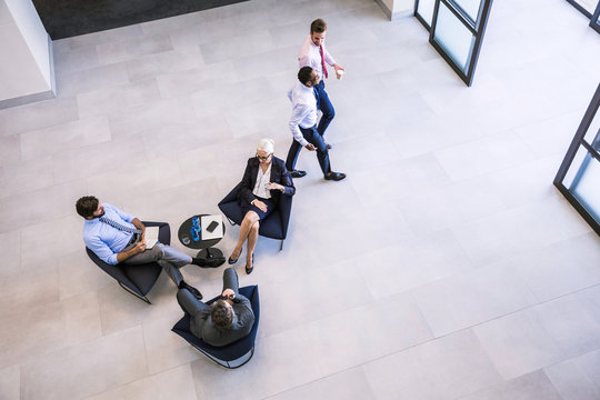 High angle view of businesswoman and men meeting in office atrium