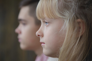 Profiles of little sister and young brother. Shallow depth of field, focus on girl.