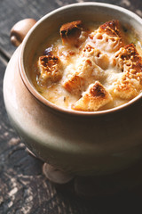 Onion soup in the ceramic pot on the  wooden table