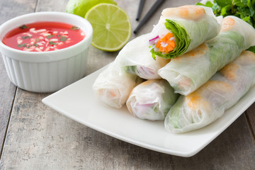 Vietnamese rolls with vegetables, rice noodles and prawns on wooden background
