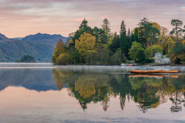 Wooden rowing boats with mountains and Autumn trees in background at Derwentwater in the English Lake District.