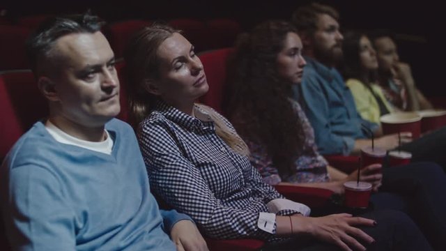 Mid-adult couple sitting in movie theater and watching film together