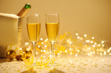 Champagne flutes on table decorated with streamer and gold confe