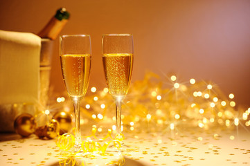 Champagne flutes on table decorated with streamer and gold confe