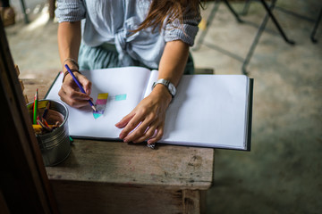 The girl with pencils, the Young girl draws on standard sheet, dressed in a blue skirt and a striped shirt, drawing lessons, the brunette