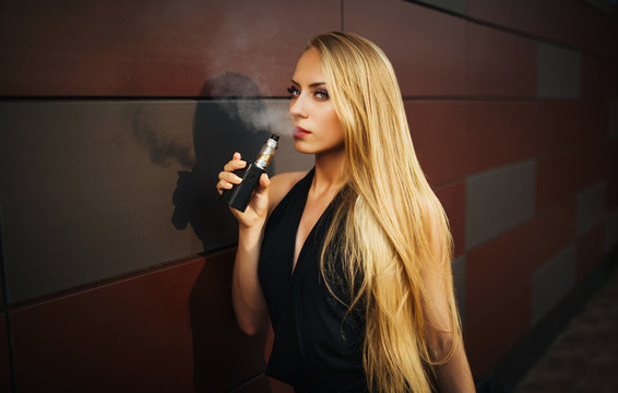 Portrait of sexy young vaping girl. Vapor concept. Vaping e-Cigarette. Close-up.