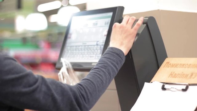 Young woman weighing the fruits with electric scales with computer screen in the supermarket.