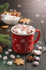 Hot chocolate with marshmallows and spices on dark wooden background. Holiday concept, bright shiny background, selective focus, vertical with copy space.