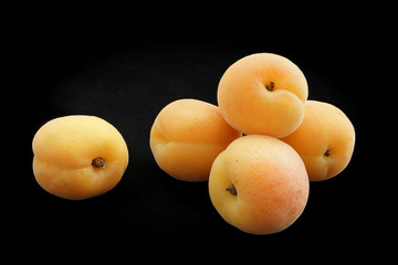 Apricots of yellow color on a black background