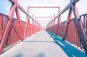 Red bridge with metal structure. Lines in perspective, long pedestrian crossing.