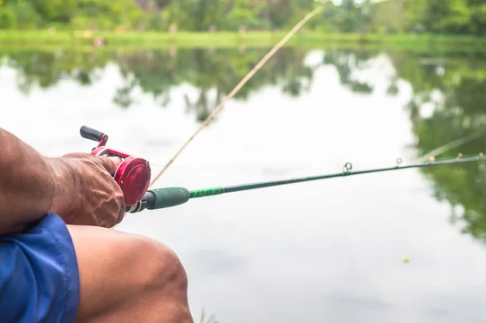 Man sitting holding a fishing rod. Fishing on lake. Stock Photo