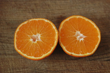 Several mandarin oranges cut in half on a wooden background.