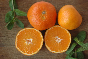 Several mandarin oranges cut in half on a wooden background.