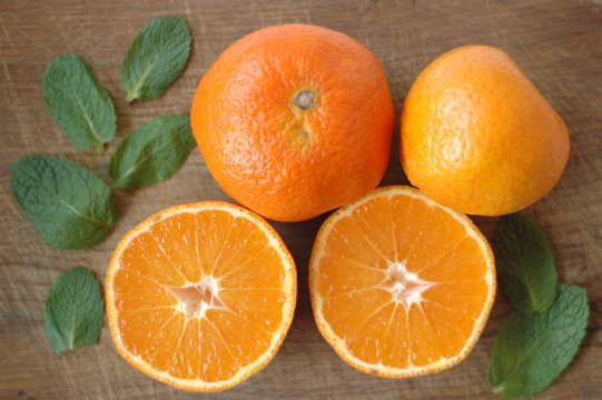 Several mandarin oranges cut in half on a wooden background.