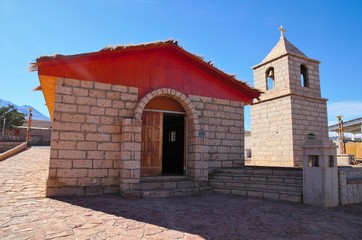 Fototapeta premium Low angle view of the old church in Socaire made out of bricks with a blue sunny sky close to San Pedro de Atacama in Chile, South America