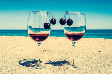 Glasses of wine and cherries near the sea