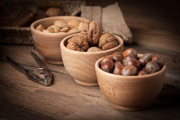 Walnuts, hazelnuts and almonds in-shell in wooden bowl.