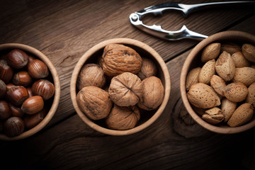 Walnuts, hazelnuts and almonds in-shell in wooden bowl.