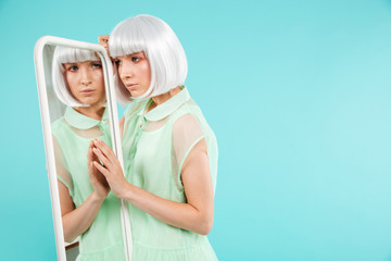 Pretty blonde young woman standing and looking at the mirror