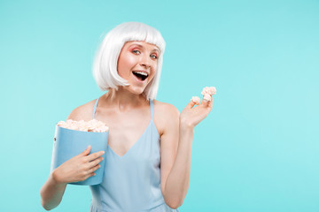 Cheerful beautiful young woman holding box of marshmallows