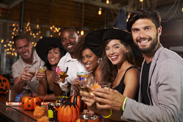Friends enjoying a Halloween party at a bar look to camera