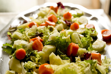 Salad varied on a metal tray. Shooting horizontal to taking advantage of the natural light coming through a window.