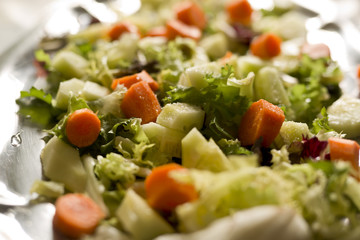 Salad varied on a metal tray. Shooting horizontal to taking advantage of the natural light coming through a window.