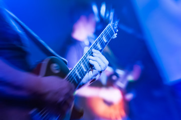 musician playing electric guitar under blue stage stage lighting - obrazy, fototapety, plakaty