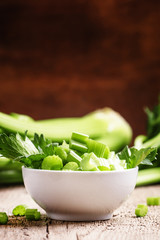 Fresh sliced celery in a white bowl on a vintage wooden backgrou