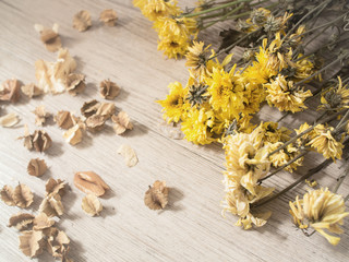 Fototapeta premium Yellow dried flowers on rustic wooden planks background ( Vintage tone color )