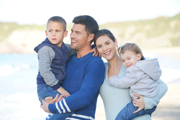 Happy family of four standing at the beach, fall vacation