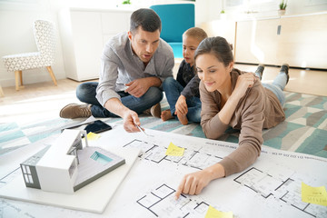 Family at home looking at future house blueprint and model
